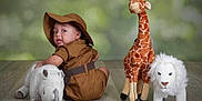 Zenith is registered to the contest to win money with this photo: animal_toys, baby, binoculars, child, cute, flooring, giraffe, green_background, hat, indoor, lion, looking_back, plush_toy, portrait, rhino, safari_outfit, stuffed_animal, toy, wooden_floor, young_child