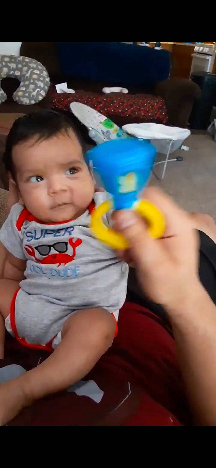 Ambrose is registered to the contest to win money with this photo: baby, baby_toddler_clothing, chair, cheek, child, finger, fun, hand, happy, human_leg, leisure, mouth, party, person, sitting, skin, thigh, thumb, toddler, toy