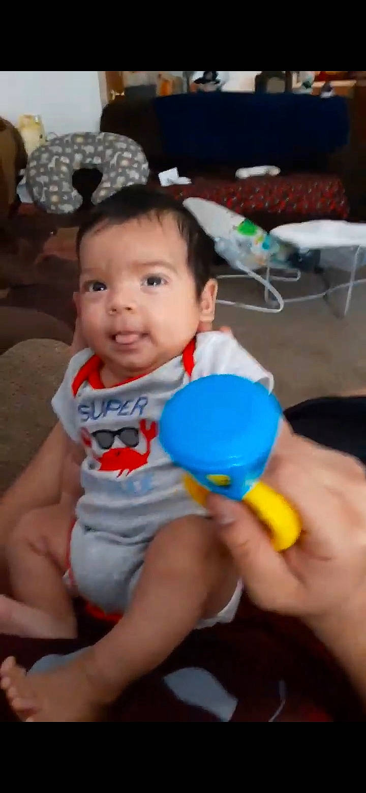 Ambrose is registered to the contest to win money with this photo: baby, baby_playing_with_toys, baby_toddler_clothing, chair, electric_blue, facial_expression, finger, fun, hair, hairstyle, hand, happy, head, leisure, party_supply, person, skin, smile, thigh, toddler
