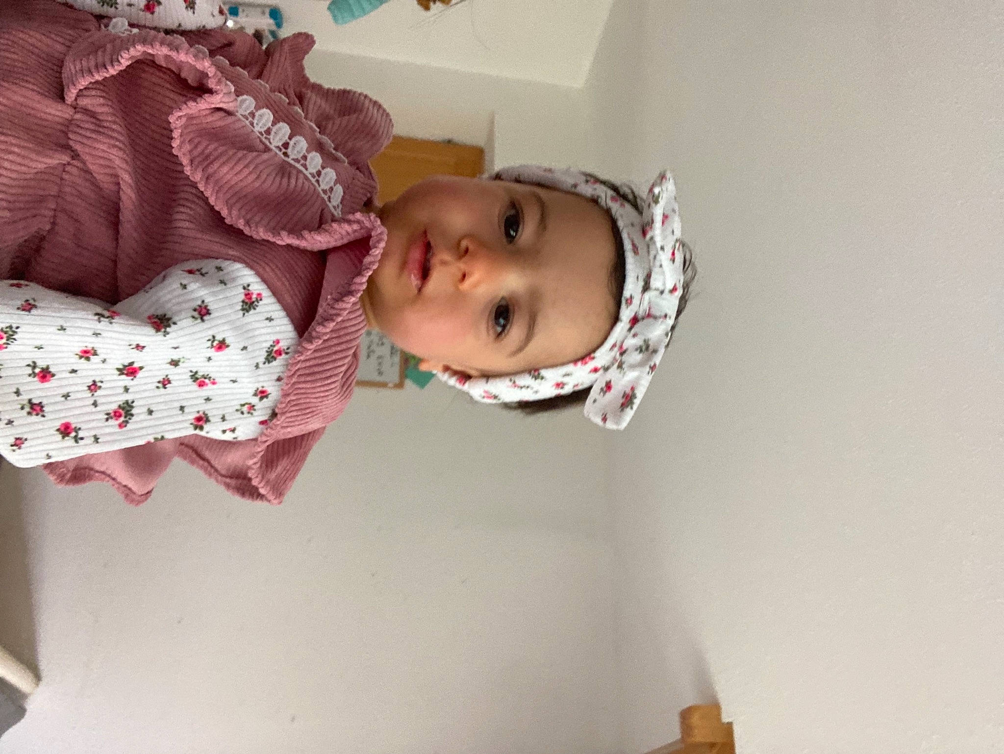 Noëline participe au concours pour gagner de l'argent avec cette photo : baby, baby_products, baby_toddler_clothing, carmine, cheek, child, comfort, dress, eyelash, fashion_accessory, happy, headgear, headwear, jacket, pattern, person, pink, plant, room, sleeve