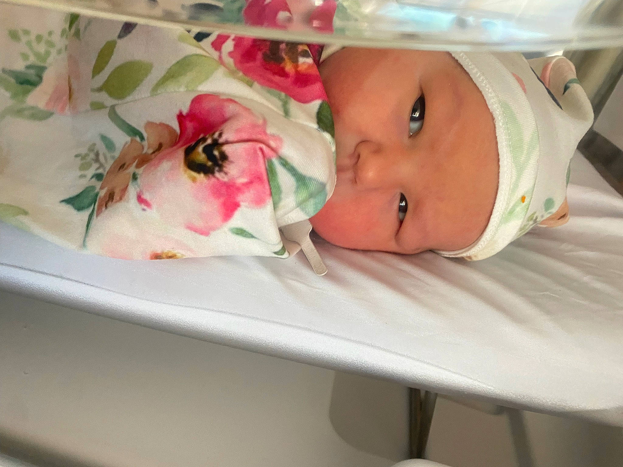 Esme is registered to the contest to win money with this photo: arm, baby, baby_products, baby_toddler_clothing, child, comfort, event, eyelash, face, flower, hat, headgear, headwear, linens, lip, person, petal, rose, skin, sleeve