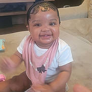 Zuri is registered to the contest to win money with this photo: baby, infant, smiling, bib, sitting, indoor, couch, toy, headband, drool, chubby_cheeks, eyes, teeth, hand_motion, portrait, cute, family_room, soft_lighting, skin, happy