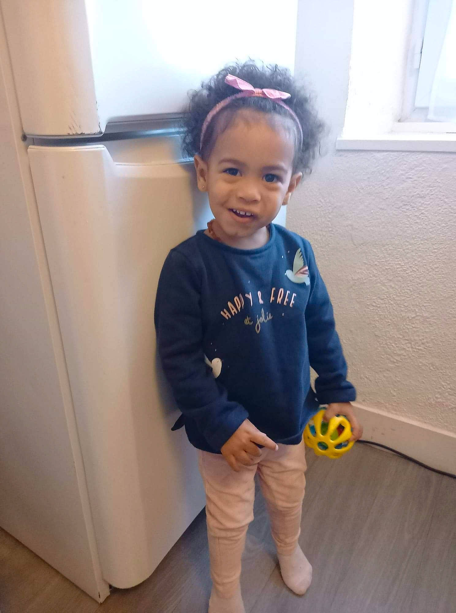 Maëlia participe au concours pour gagner de l'argent avec cette photo : baby, baby_toddler_clothing, child, electric_blue, floor, flooring, fun, hair, happy, hardwood, person, skin, sleeve, smile, sweatpant, t_shirt, toddler, waist, window, window_blind