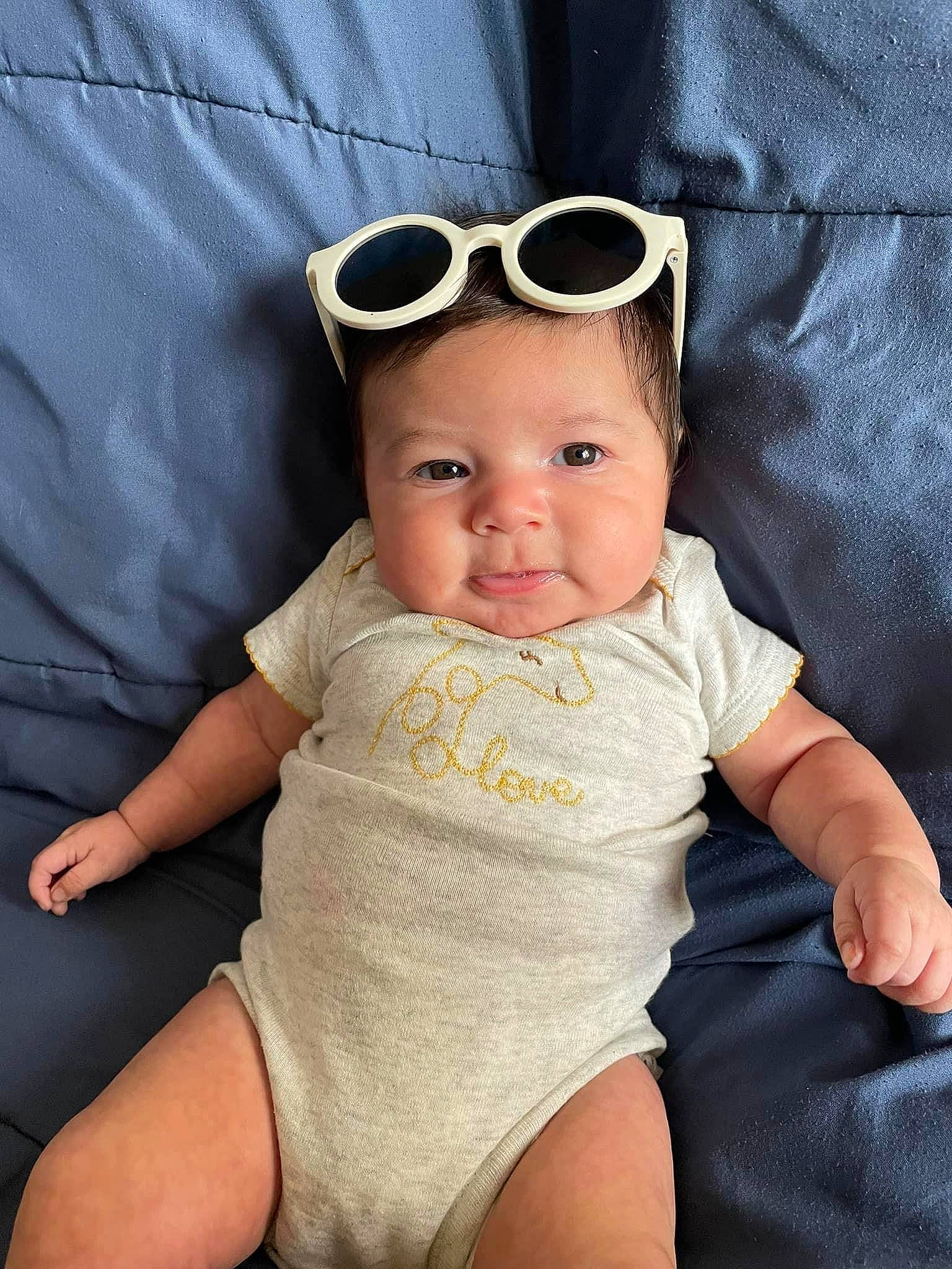 Letty is registered to the contest to win money with this photo: baby, baby_products, baby_toddler_clothing, cheek, chin, comfort, eyewear, face, finger, goggles, headwear, knee, lip, pattern, person, skin, sleeve, sunglasses, t_shirt, thigh