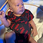 Kaiden is registered to the contest to win money with this photo: baby, infant, onesie, puma, clothing, cushion, seat, indoor, person, child, newborn, face, expression, hand, legs, sock, fabric, soft, light, shadow