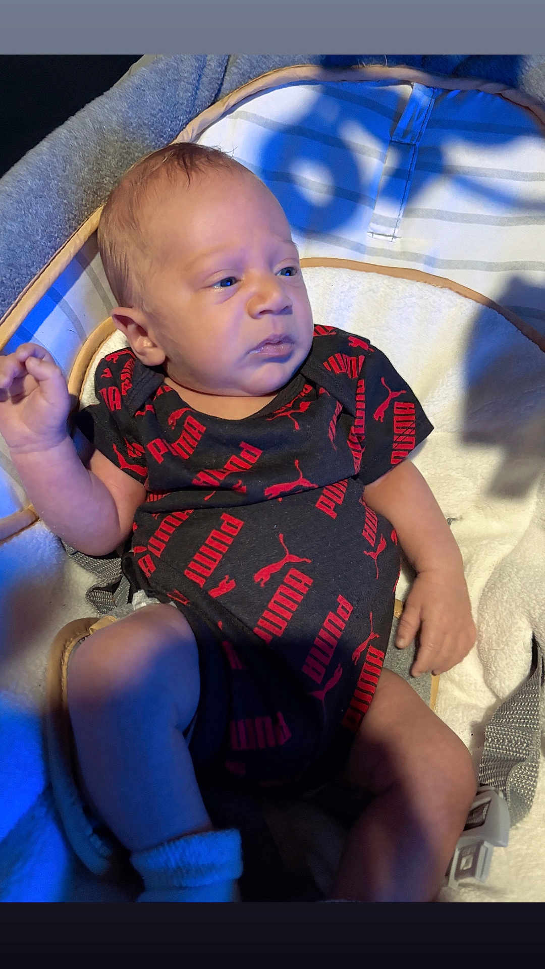 Kaiden is registered to the contest to win money with this photo: baby, infant, onesie, puma, clothing, cushion, seat, indoor, person, child, newborn, face, expression, hand, legs, sock, fabric, soft, light, shadow