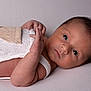 baby, newborn, infant, face, eyes, hair, skin, hand, fingers, knitted_clothing, romper, lying_down, closeup, portrait, studio_lighting, neutral_background, soft_texture, peaceful, curious, newborn_photography
