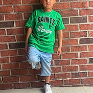 Zayden is registered to the contest to win money with this photo: boy, brick_wall, casual_pose, child, cool, daylight, denim_shorts, fashion, green_tshirt, outdoor, person, portrait, serious_expression, short_hair, sidewalk, standing, street_style, urban, white_sneakers, young