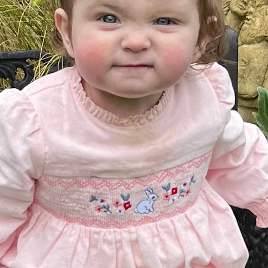 Lily Rose joined the competition — help win amazing prizes! baby, bench, bow, child, clothing, cute, expression, face, garden, grass, greenery, nature, outdoor, person, pink_dress, plants, portrait, sitting, toddler, young_child