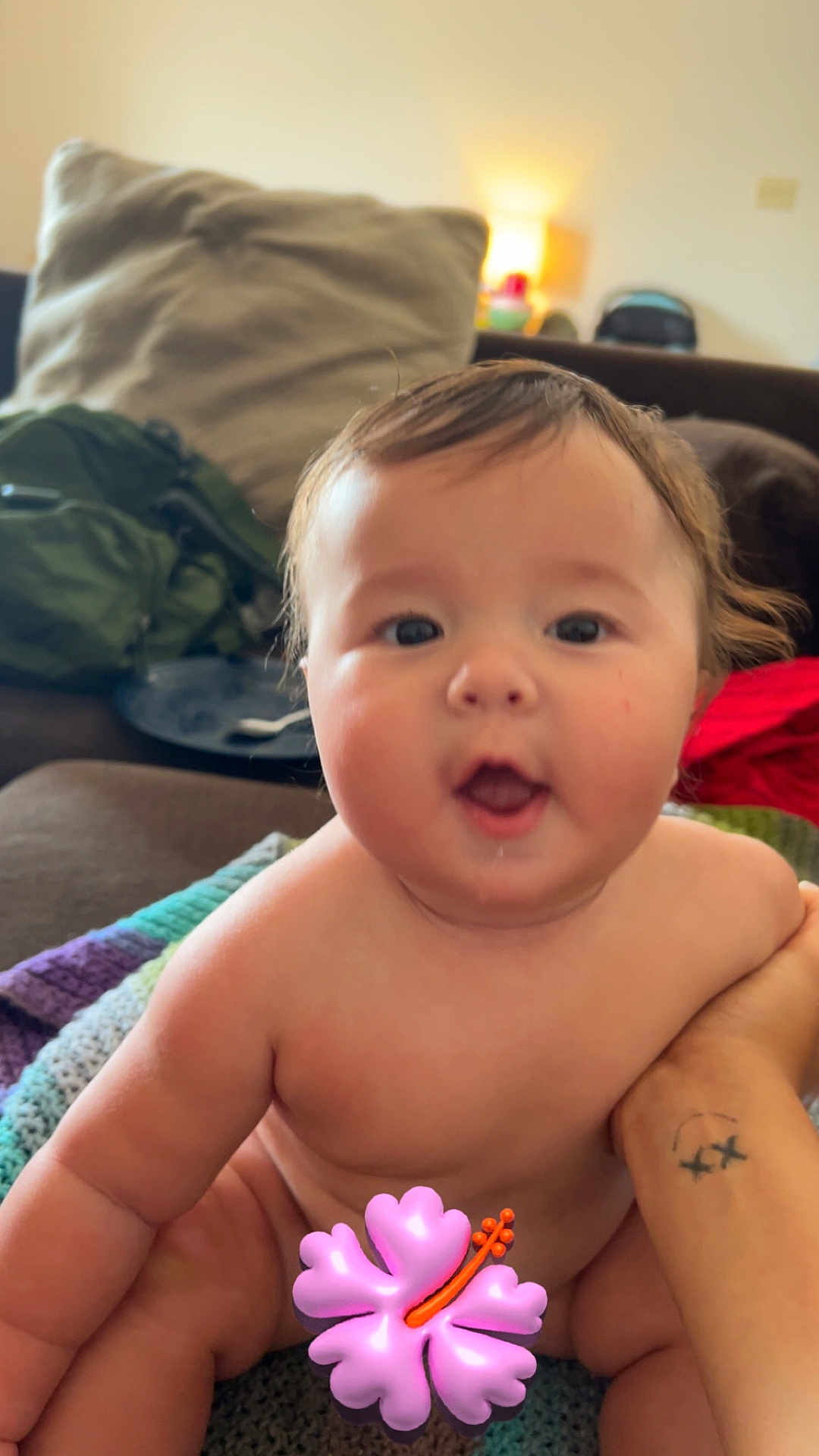 Jaxon joined the competition — help win amazing prizes! baby, infant, child, naked, smiling, happy, face, arm, tattoo, blanket, sofa, couch, indoor, person, skin, hand, expression, cute, holding, flower_emoji