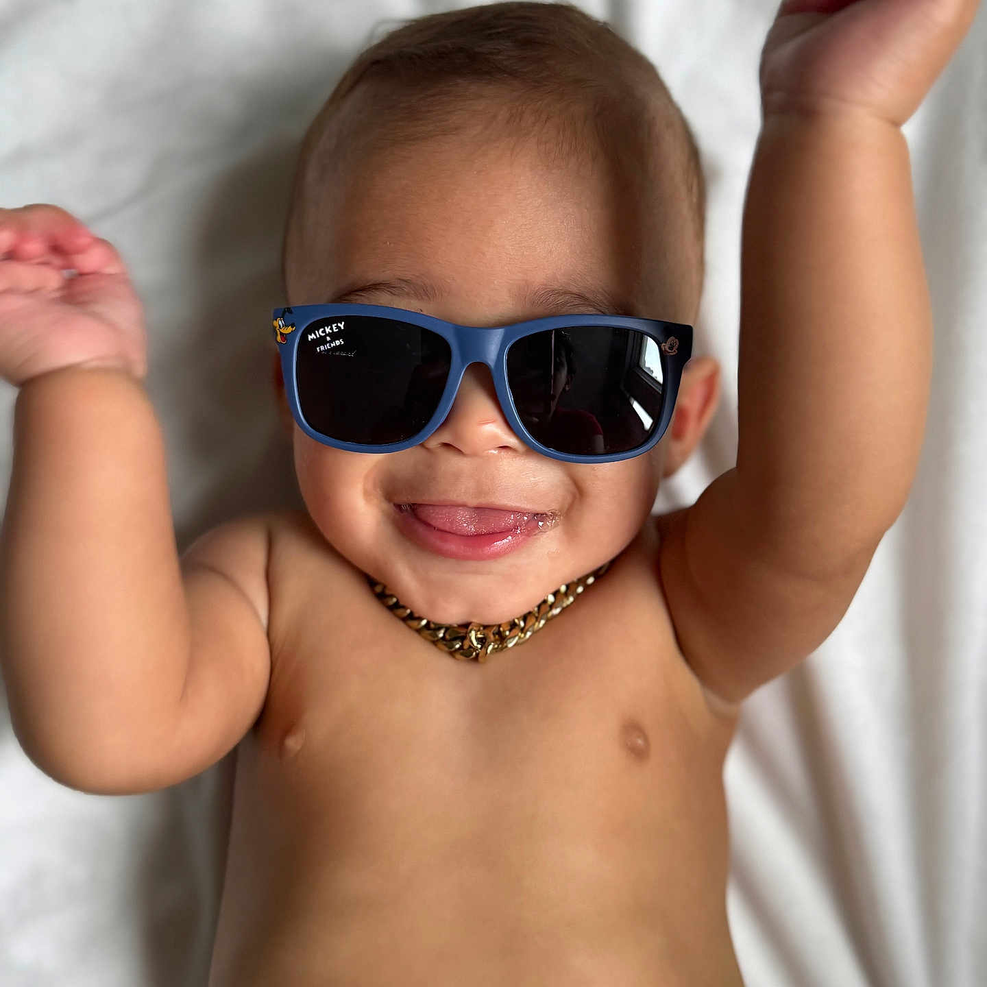 Asafe joined the competition — help win amazing prizes! arms_up, baby, bare_chest, child, close_up, cute, fun, gold_chain, happy, infant, lying_down, mickey_mouse, person, playful, portrait, skin, smile, sunglasses, tongue, white_blanket