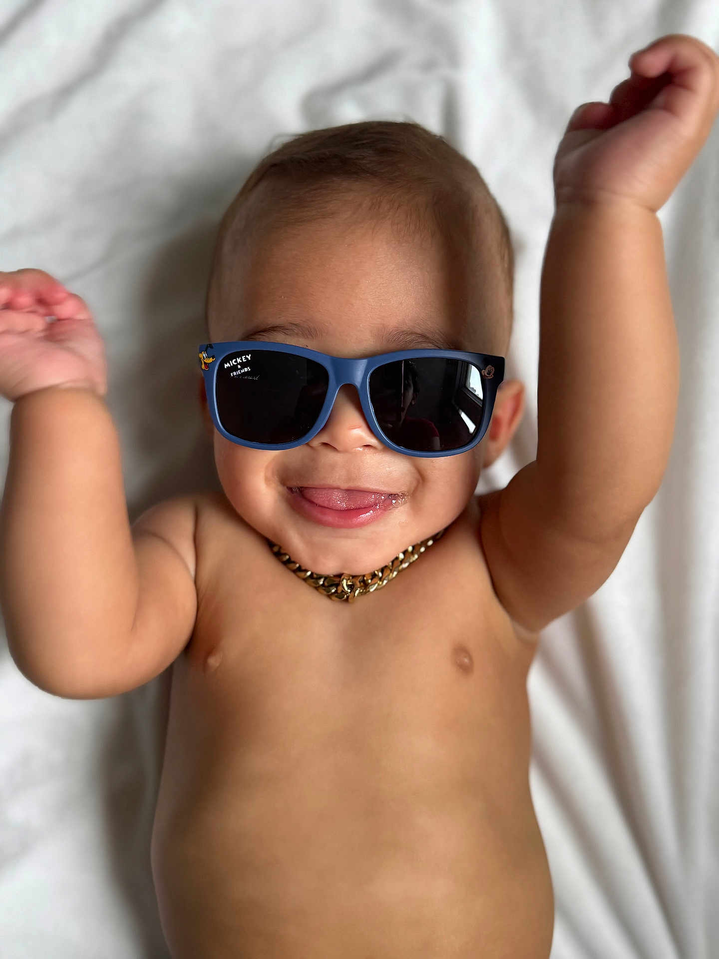 Asafe joined the competition — help win amazing prizes! baby, child, sunglasses, mickey_mouse, tongue, smile, arms_up, gold_chain, bare_chest, playful, happy, infant, cute, portrait, lying_down, white_blanket, skin, person, close_up, fun