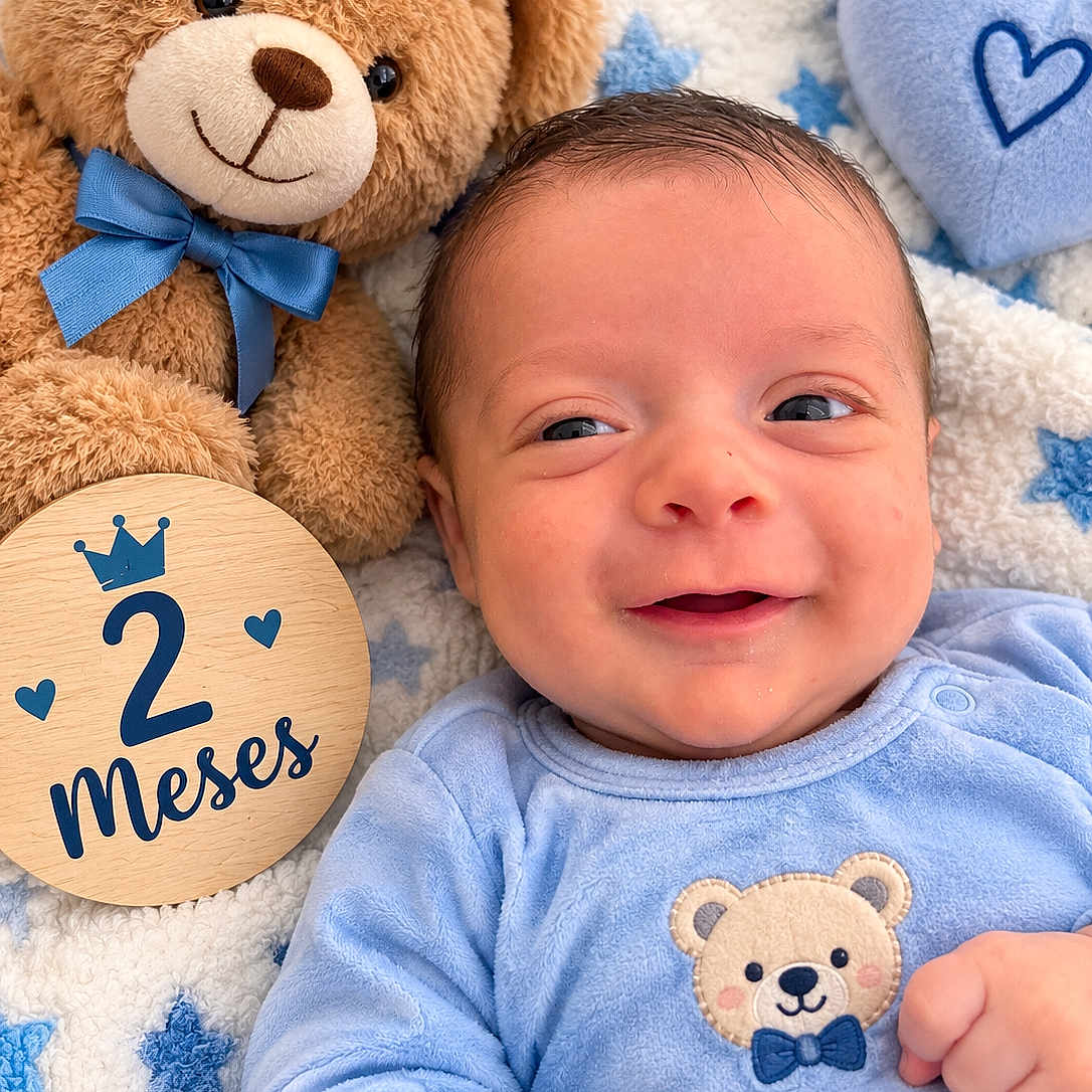 Jacob is registered to the contest to win money with this photo: baby, newborn, infant, smiling, portrait, close_up, face, blue_clothing, teddy_bear, plush_toy, blanket, stars, heart, milestone, two_months, wooden_sign, indoor, lying_down, cute, family_photo