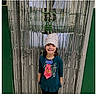 child, girl, smiling, paper_crown, tie, celebration, school, streamers, door, green_wall, long_sleeve_shirt, standing, indoors, portrait, happy, decoration, costume, person, holiday, event