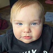 Samuel joined the competition — help win amazing prizes! baby, child, blue_eyes, blond_hair, close_up, face, indoor, curious, calm, black_shirt, person, infant, portrait, human, cute, young_child, soft_light, wood_floor, clothing, expression