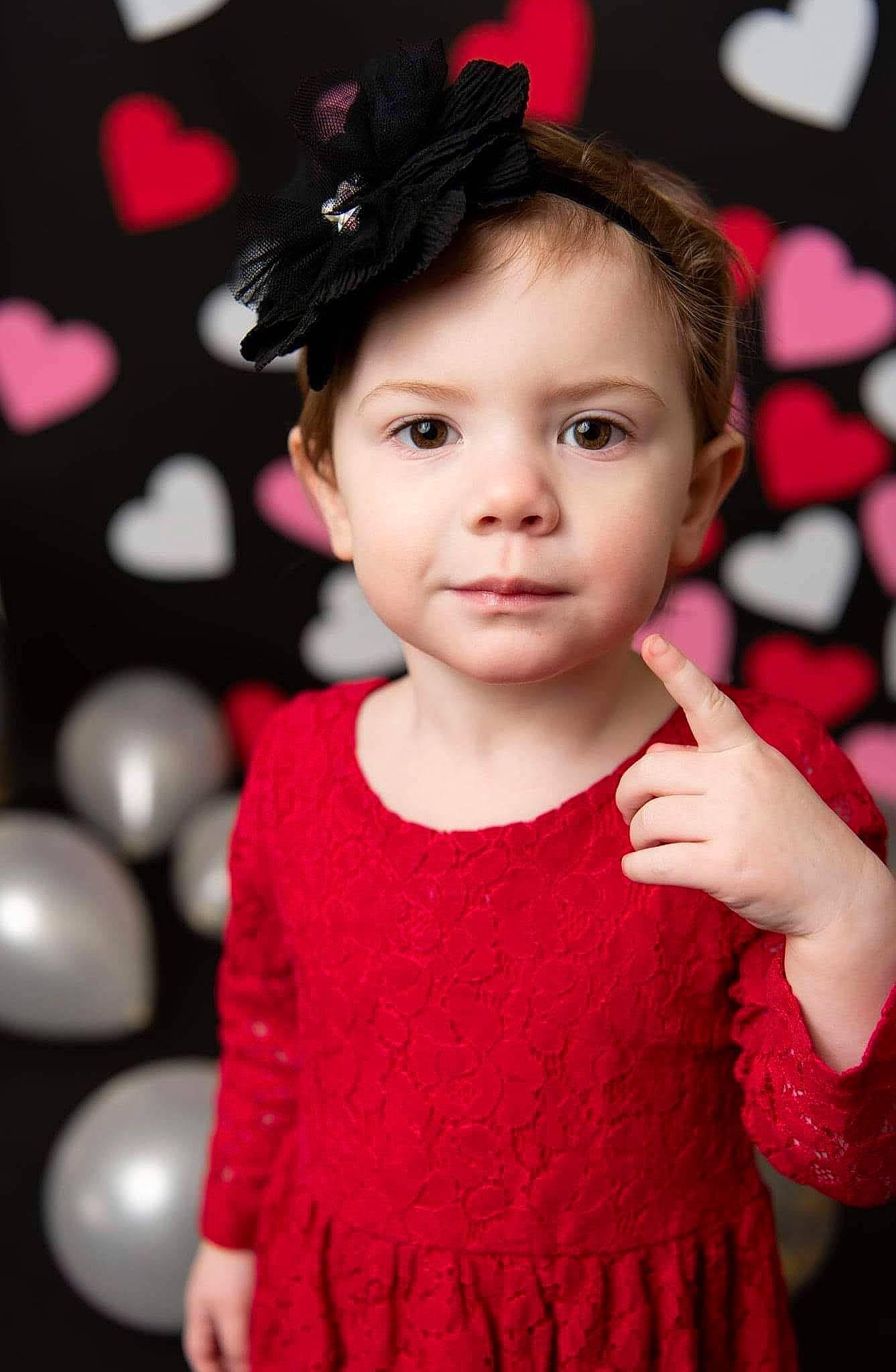 Luella is registered to the contest to win money with this photo: baby_toddler_clothing, cheek, chin, eyelash, face, fashion, flash_photography, gesture, happy, human_body, lip, magenta, organ, person, pink, red, skin, sleeve, standing, toddler