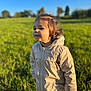 toddler, child, jacket, beige, outdoor, field, grass, sunlight, blue_sky, curly_hair, portrait, person, nature, daylight, young_child, cute, happy, standing, clothing, warm_clothes