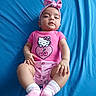 Doralynn joined the competition — help win amazing prizes! baby, infant, pink_clothing, headband, hello_kitty, blue_background, lying_down, socks, cute, child, portrait, indoor, playful, soft_texture, skin, hands, legs, face, expression, watermark