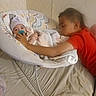 baby, child, siblings, infant, toddler, pacifier, bouncer, red_shirt, cuddling, bedroom, bed, blanket, pillow, sleeping, sitting, family, portrait, indoors, soft_lighting, cozy