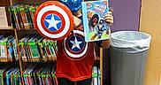 Joseph joined the competition — help win amazing prizes! books, bookshelves, captain_america, child, clothing, comic_book, costume, fan, helmet, indoor, library, marvel, playful, portrait, reading, red_white_blue, school, shield, standing, superhero