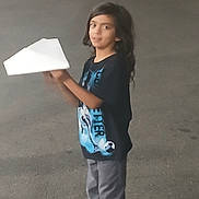 Joseph joined the competition — help win amazing prizes! black_shirt, casual_clothing, child, concrete, daylight, face, full_body, gray_pants, hands, long_hair, outdoors, paper_airplane, paper_object, person, photograph, portrait, side_profile, smiling, standing, wall