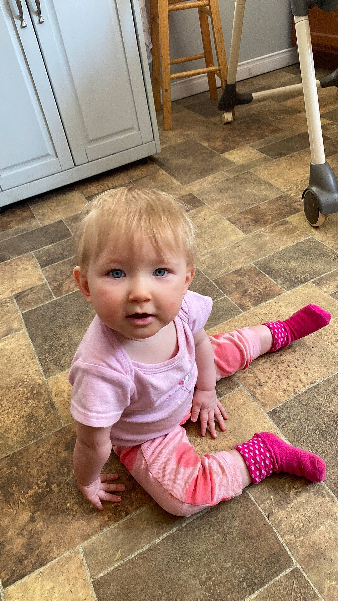 Brooklyn is registered to the contest to win money with this photo: baby, baby_toddler_clothing, cabinetry, cheek, child, door, floor, flooring, fun, grass, hardwood, leg, person, pink, road_surface, sitting, smile, toddler, white, wood