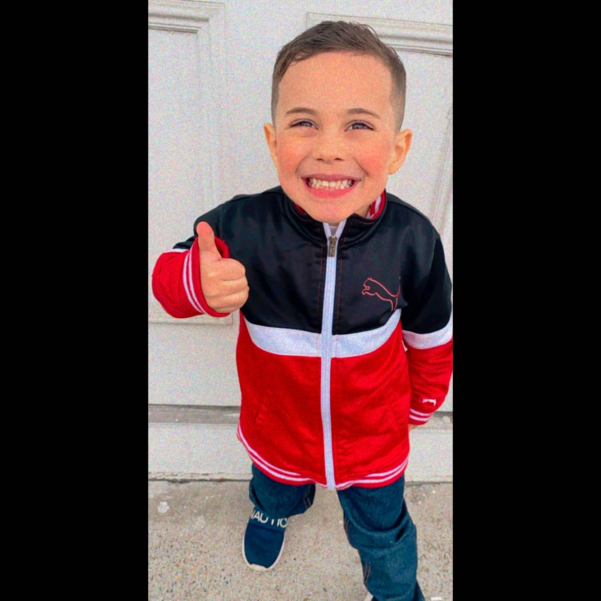 Bernardo is registered to the contest to win money with this photo: baby, baby_toddler_clothing, denim, electric_blue, face, font, gesture, happy, head, hood, jersey, joy, outerwear, person, personal_protective_equipment, sleeve, smile, sportswear, t_shirt, thumb