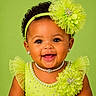 baby, child, portrait, smiling, curly_hair, headband, pearl_necklace, earrings, green_dress, tulle, decorative_flower, close_up, happy, cute, studio_photo, fashion, accessories, infant, bright_background, joyful