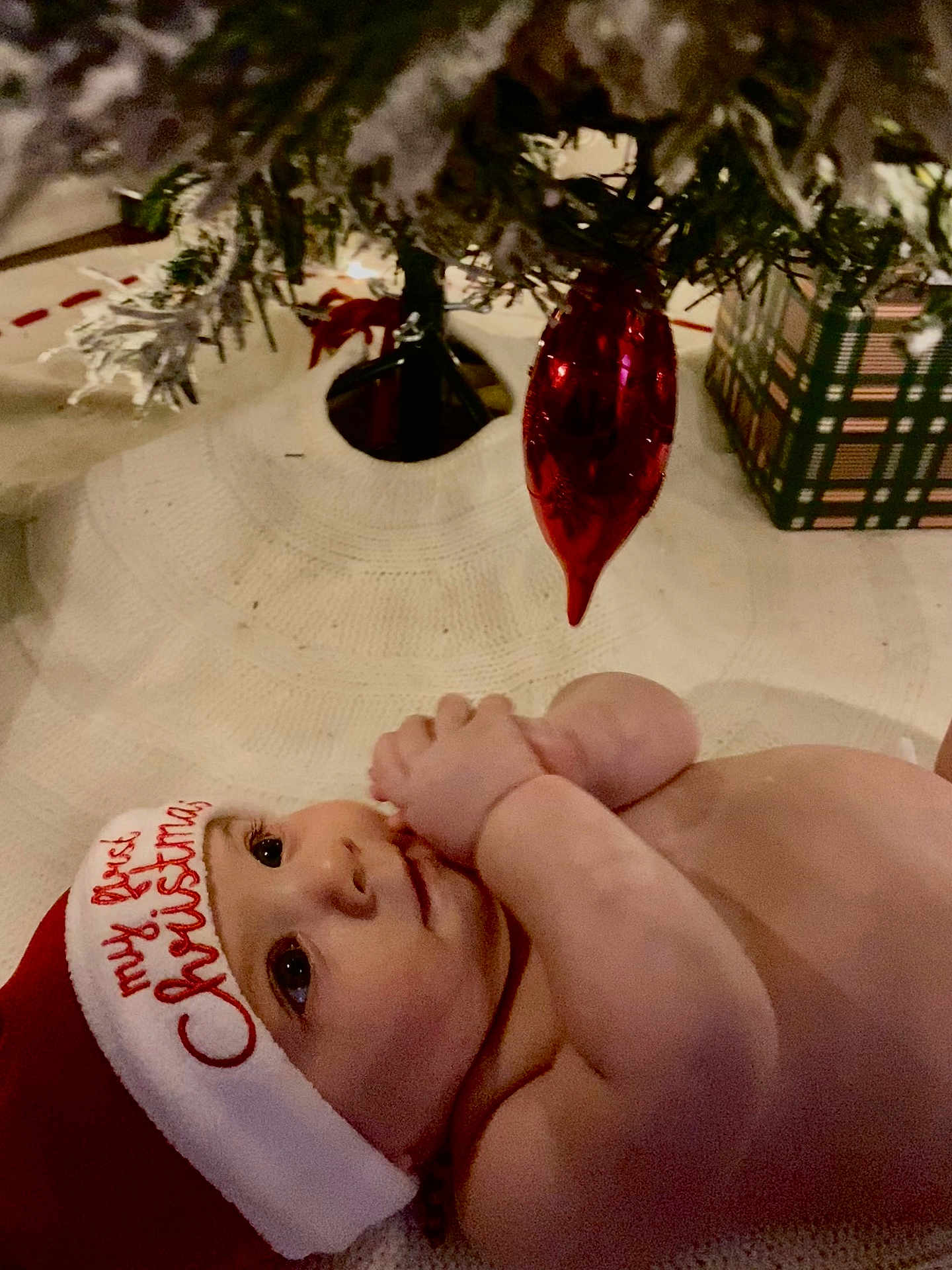 Copeland is registered to the contest to win money with this photo: baby, infant, christmas_hat, holiday, ornament, red, tree, christmas_tree, blanket, cute, festive, holiday_decoration, child, indoors, celebration, smiling, holiday_season, sitting, person, face