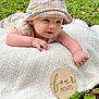 Copeland is registered to the contest to win money with this photo: baby, blanket, child, crawling, cute, four_months, grass, greenery, happy, hat, infant, nature, outdoor, person, plaid_hat, portrait, smiling, tummy_time, wooden_sign, young_child
