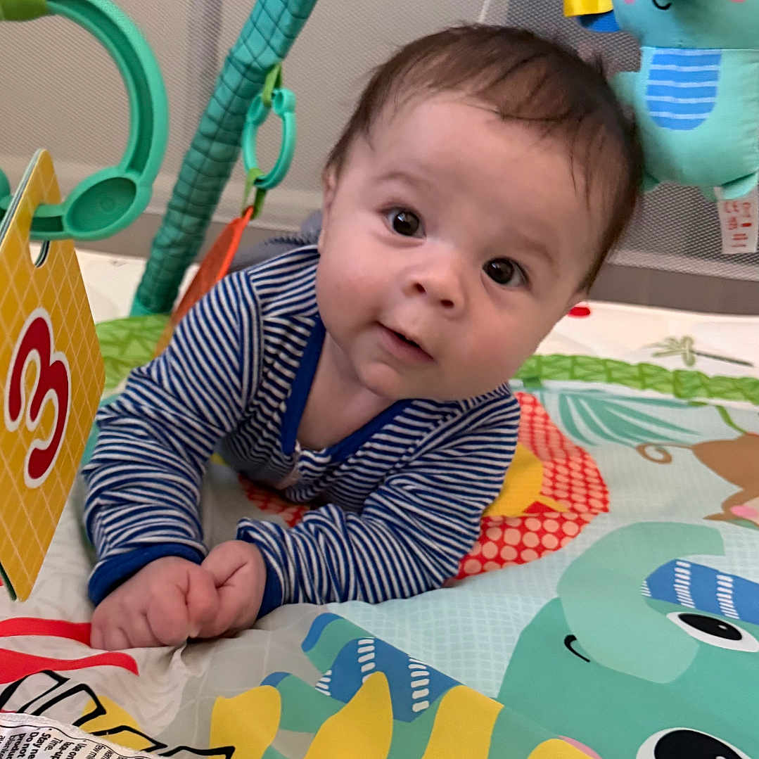 Ethan joined the competition — help win amazing prizes! baby, child, play_mat, toys, striped_clothing, indoor, curious, face, infant, colorful, playpen, hand, smiling, cute, young, person, floor, activity, bright, happy