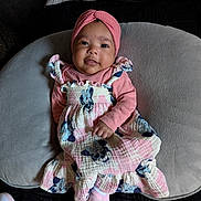 Anahí is registered to the contest to win money with this photo: baby, child, infant, pink_clothing, headwrap, dress, socks, cushion, bedspread, quilt, portrait, smiling, indoor, comfortable, cute, person, young_child, fabric, soft_texture, relaxing