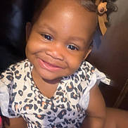Laiyani is registered to the contest to win money with this photo: baby, child, clothing, curly_hair, cute, face, hair_bow, happy, holding, indoor, leopard_print, person, playful, portrait, sitting, skin, smiling, toddler, toy, young_child