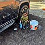 toddler, child, car, suv, soap, bucket, rag, mud, outdoor, cleaning, vehicle, wheel, clothing, footwear, garage, toy_bike, floor, plastic_bucket, hand, person