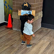 Andre Ariel joined the competition — help win amazing prizes! toddler, child, indoor, wooden_floor, carved_bear, statue, orange_cone, pointing, white_shirt, brown_pants, shoes, brick_wall, floor, person, walking, young_child, casual_clothing, wall_art, flooring, playful