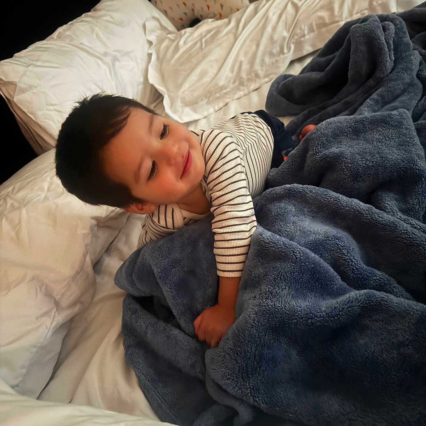 Andre Ariel is registered to the contest to win money with this photo: bed, blanket, blue, child, comfort, cozy, cute, happy, indoors, nursing_pillow, pillow, portrait, rest, sleepwear, smile, soft_texture, striped_shirt, toddler, white, young_child