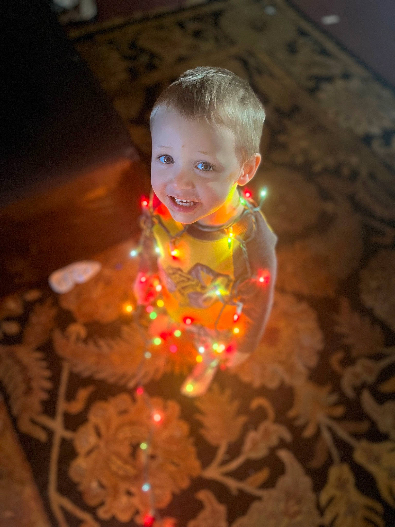 Phoenix is registered to the contest to win money with this photo: baby, cheek, christmas, christmas_ornament, darkness, event, flash_photography, floor, flooring, fun, glass, happy, head, human_body, joy, ornament, person, smile, space, toddler