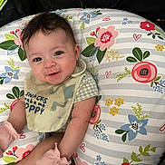 Makayla is registered to the contest to win money with this photo: baby, bib, child, clothing, colorful, comfort, cushion, cute, face, floral_pattern, happy, indoors, infant, laying_down, mittens, person, portrait, smile, soft_toys, young_child