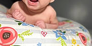 Makayla is registered to the contest to win money with this photo: baby, infant, face, expression, open_mouth, eyes, skin, pillow, floral_pattern, colorful, lying_down, cute, child, indoors, soft_focus, person, newborn, head, hands, blanket