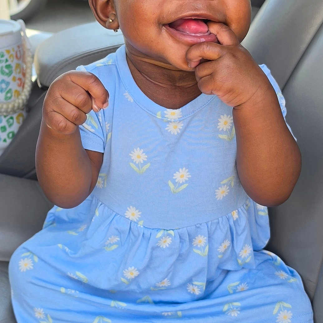 Ohana is registered to the contest to win money with this photo: baby, child, girl, dressed, blue_dress, headband, sitting, car_seat, smiling, happy, cute, finger_in_mouth, barefoot, indoors, person, portrait, infant, skin, clothing, accessory
