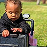black_hoodie, child, childhood, curious, daylight, face, fun, green_grass, hands, hooded_clothing, nature, outdoor, play, portrait, small_vehicle, sunny, toddler, toy_car, vehicle, young_child