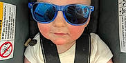 Louis is registered to the contest to win money with this photo: baby, blanket, car_seat, child, closeup, clothing, cute, face, hands, indoor, infant, person, portrait, rosy_cheeks, safety, seatbelt, small, sunglasses, white_shirt, young