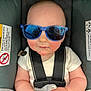 baby, blanket, car_seat, child, closeup, clothing, cute, face, hands, indoor, infant, person, portrait, rosy_cheeks, safety, seatbelt, small, sunglasses, white_shirt, young