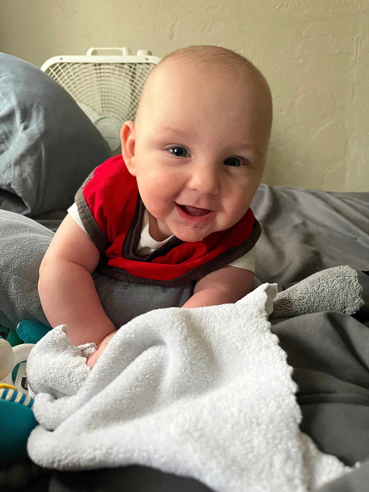 Louis joined the competition — help win amazing prizes! arm, baby, bed, blanket, child, comfort, eyes, fabric, face, happy, head, home, indoor, infant, mouth, person, red_bib, skin, smiling, toy