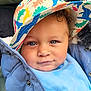 child, toddler, baby, face, blue_eyes, curly_hair, hat, colorful_hat, dinosaur_pattern, jacket, blue_jacket, bib, clothing, portrait, smile, cute, outdoor, warm_clothing, infant, person