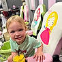 Hazel is registered to the contest to win money with this photo: toddler, child, smiling, orange_juice, glass, straw, salon_chair, princess_cartoon, hair, face, hand, green_tshirt, indoor, pedicure_station, pink, green, table, happy, young_child, cute