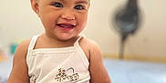 Teanivai a rejoint le concours — aidez-le/la à gagner de superbes lots ! baby, child, smiling, happy, face, skin, hand, white_clothing, tank_top, sitting, indoors, blurred_background, cute, infant, portrait, young_child, person, short_hair, expression, human