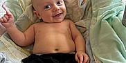 Silas joined the competition — help win amazing prizes! baby, smiling, indoor, quilt, blanket, couch, floor, hand, waving, child, happy, portrait, clothing, bare_chest, head, face, skin, comfort, relaxed, home