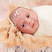 Kobi is registered to the contest to win money with this photo: newborn, baby, infant, wrapped, blanket, headband, pearls, soft_texture, face, eyes, closeup, portrait, cute, resting, delicate, skin, babywear, indoors, warm_colors, peaceful