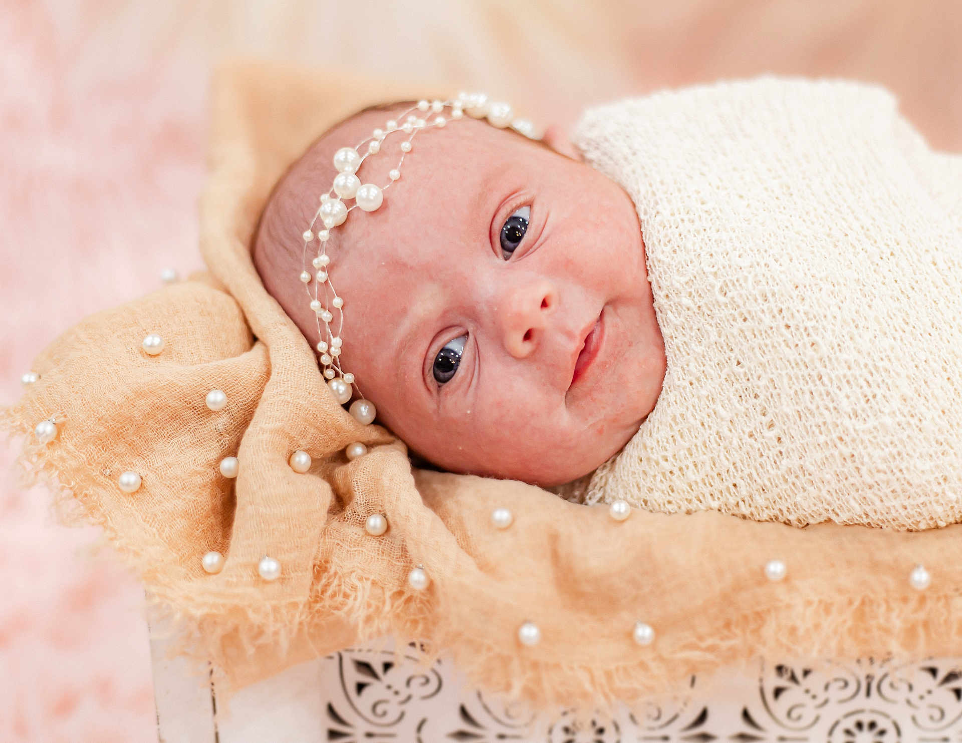 Kobi is registered to the contest to win money with this photo: newborn, baby, infant, wrapped, blanket, headband, pearls, soft_texture, face, eyes, closeup, portrait, cute, resting, delicate, skin, babywear, indoors, warm_colors, peaceful
